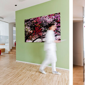 Helles, modernes Wartezimmer einer Arztpraxis mit weißen Stühlen und dekorativer Wandkunst.